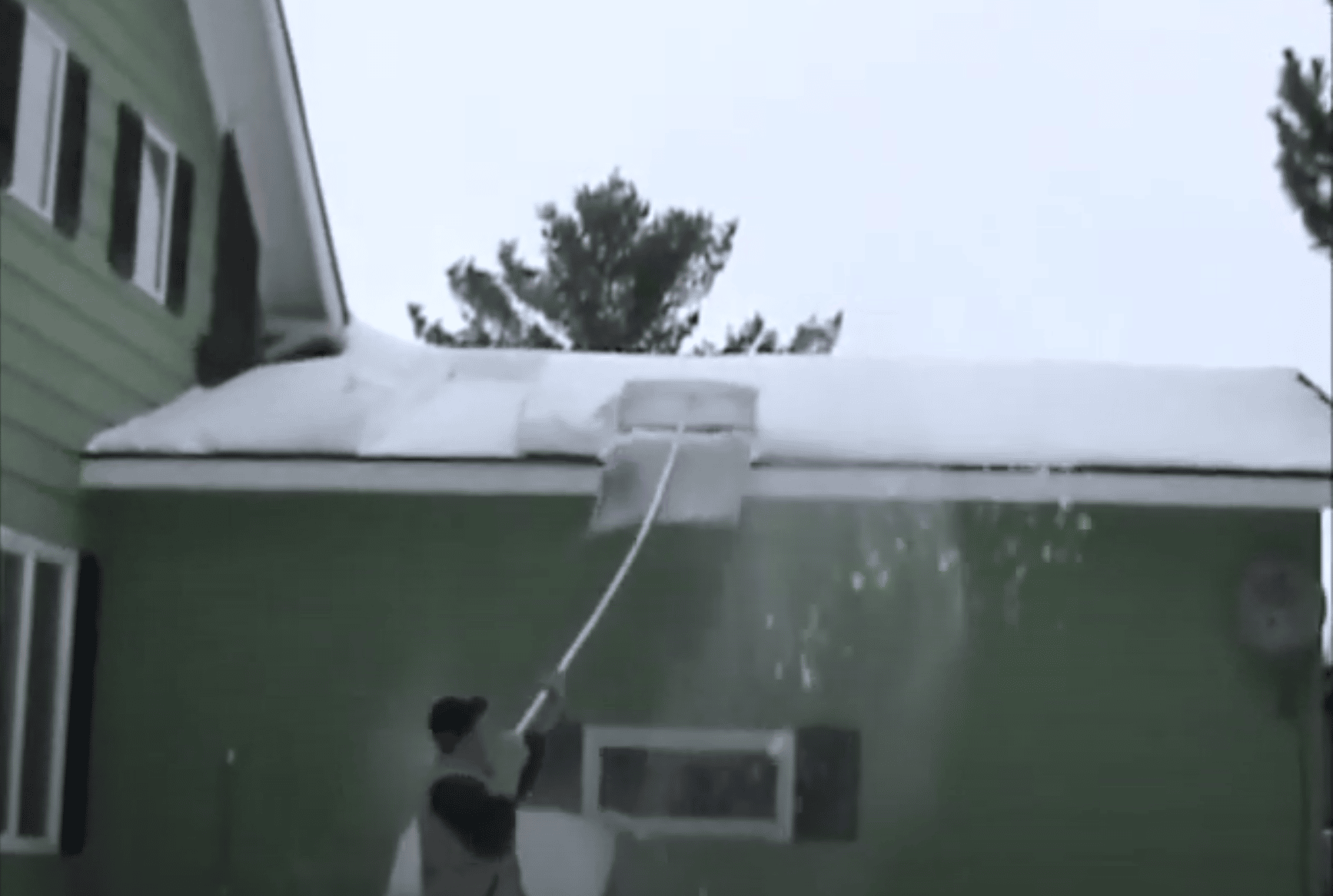 Snow covered roof being cleared off by a Roof Razor